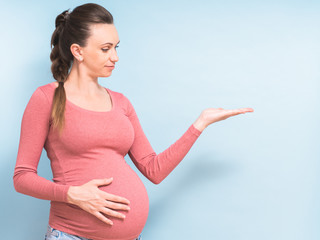 Young beautiful pregnant woman over isolated blue background pointing finger to the side showing product. Presenting your product. Copy space - 371054155
