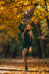Young woman in a beautiful autumn park, raises a scarf up.