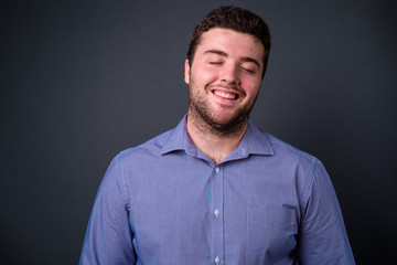 Fototapeta premium Portrait of happy young handsome overweight bearded businessman