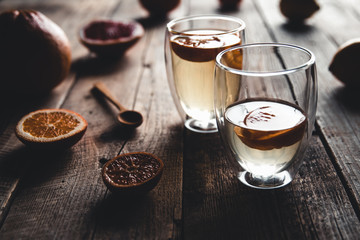 Citrus tea in a transparent teapot and a glass, healthy drink on a wooden background.