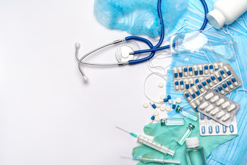 Coronavirus protection concept - stethoscope, hat, goggles, syringe and protective mask, pills, syringe on blue background