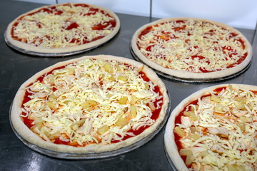 Cook in the kitchen putting the ingredients on the pizza