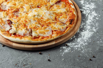 pizza with cheese, sauce and ham, bacon, salami on a gray dark background