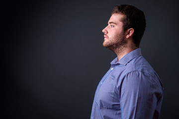 Portrait of young handsome overweight bearded businessman