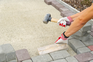 worker laying paving stones. stone pavement, construction worker laying cobblestone rocks on sand.