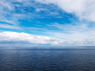Blue sky and white clouds over the lake. Small ripples on the water.