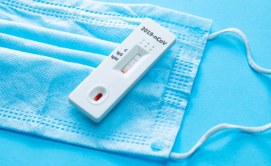 Home blood test for COVID-19 on blue background with a medical mask.