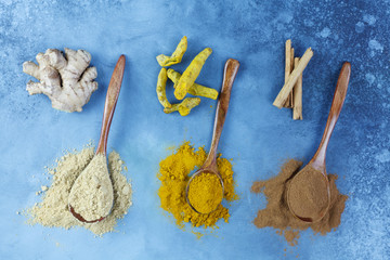 Spice. Spices on wooden spoons. Turmeric, cinnamon and ginger on a blue background. Flat lay.