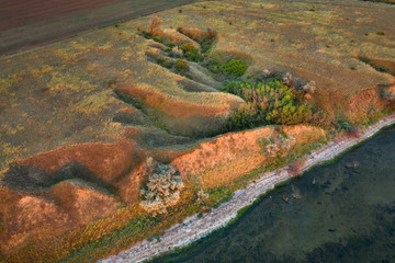 aerial view to lines and shapes of wild hills on the lake coast in sunset lights