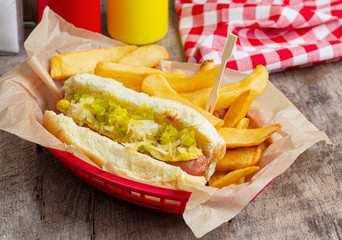 Hot dog on toasted bun with mustard, sauerkraut, and pickle relish with french fries