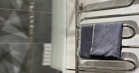 Grey towel on towel dryer in a bathroom. Copy space