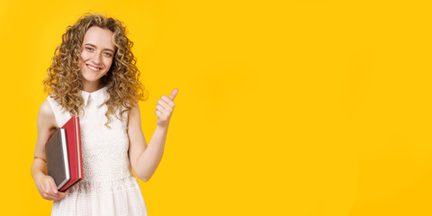 A young woman is holding a diary and a textbook. Shows gesture class. Female portrait.