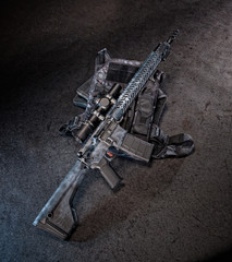 AR 15 style rifle with a magazine inserted, shot on a distressed floor with a visible sling.