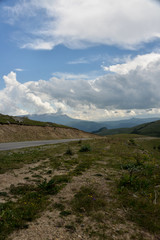 Fototapeta premium the roadbed is uneven, winding, passes through mountains and cliffs. Clouds are dark, low, with rain. A thick white fog is spreading along the road.