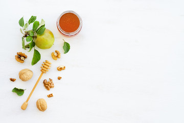 Honey, apples and walnuts on white wooden background