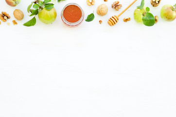 Honey, apples and walnuts on white wooden background