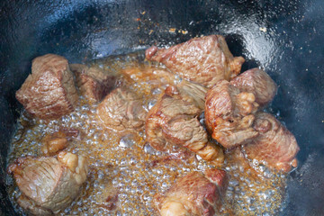 Cooking pilaf in a cauldron on the grill outside in the summer