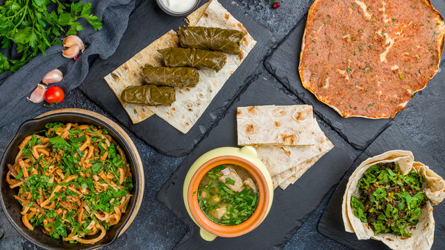 Armenian cuisine food set. Aveluk, dolma , lahmacun, Armenian cuisine on black stone table top view.