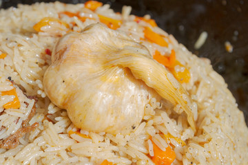 Cooking pilaf in a cauldron on the grill outside in the summer