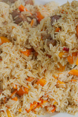 Cooking pilaf in a cauldron on the grill outside in the summer