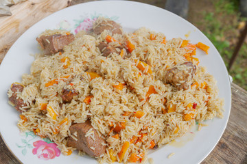 Cooking pilaf in a cauldron on the grill outside in the summer