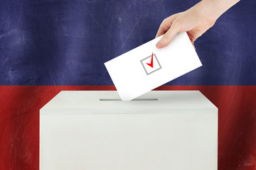 Haiti Vote concept. Voter hand holding ballot paper for election vote on polling station