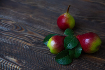 Beautiful ripe and delicious pears on a wooden background with pear tree foliage