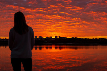 Woman looking at sunrise in a lake
