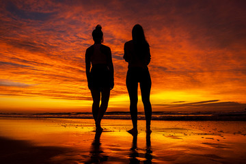 Mother and daughter watching a beautiful sunrise at Campeche beach in Florianopolis Brazil.