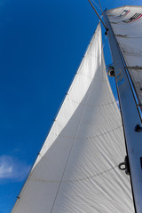 Bottom view of mast and sail of yacht on blue sky background, selective focus