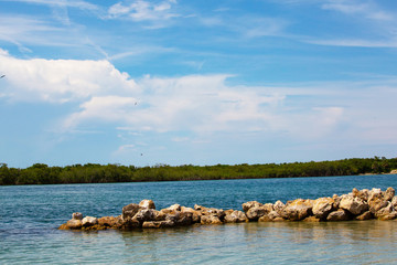 Fototapeta na wymiar Deep blue sky and whispy clouds near a rock jetty on the river