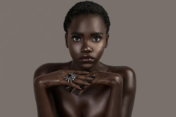A portrait of a serene young black female with short black hair, moist lips, perfectly black...