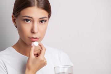 Young woman taking a pill for a headache