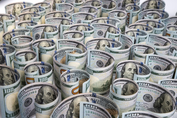 Lots of hundred dollar bills close-up rolled up on a white background. Selective focus. Blurred background.