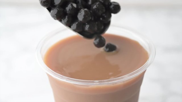 tapioca pearls splashing into milk tea