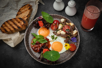 hearty breakfast - eggs with tomatoes, beans, meat, cheese and sauce on a plate
