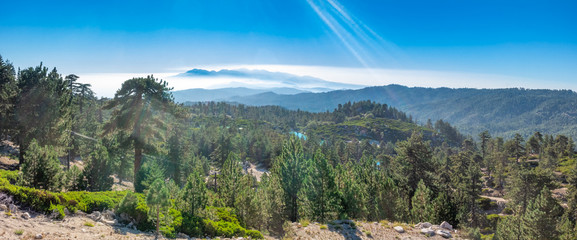 Wide panoramic of the San Bernardino mountains from the top of a local ski resort during the summer, near Running Springs, California with lens flare 