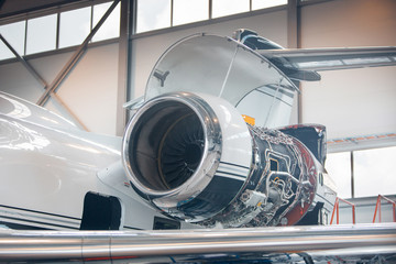 Maintenance of jet airplane in large white hangar. Private jet on restore and repair works at...