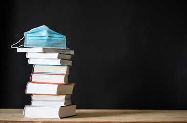 back to school during covid pandemic pile of books and medical mask
