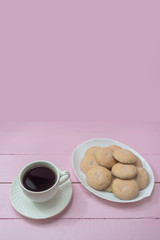 Cup of Americano coffee and homemade cookies on pink background. Copy space. The concept of romance, tenderness, coffee time