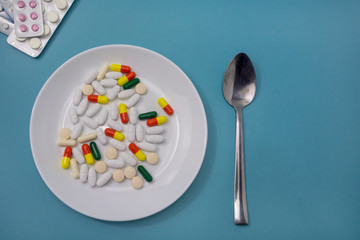 Plate with pills and capsules on blue background. Time to take your medicine. Health care,...