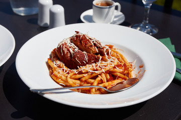 Freshly served in the restaurant pastitsada of beef with bucatini pasta. The most famous and characteristic dish from the island of Corfu in Greece. - obrazy, fototapety, plakaty