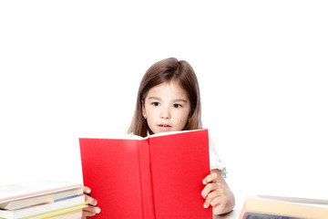 Young cute girl sitting at the table and reading a book