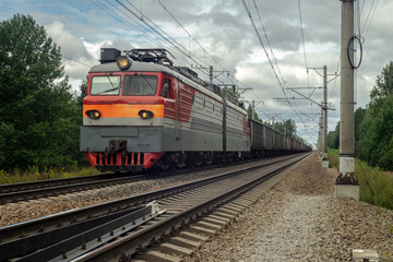 Fototapeta na wymiar Electric freight train rides on the railway and carries wagons with cargo