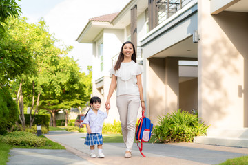 Happy Asian mother and daughter kindergarten student walking to school at morning school routine. Beginning of lessons. First day of fall. Parenthood or love and bonding expression concept.