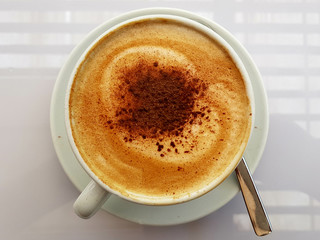 drinking a hot cup of coffee with milk / latte and foam / mug at breakfast
