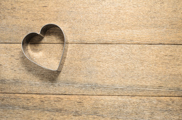 The heart of the baking dish against the background of textured ash boards is made in a rustic style. Selective focus.