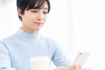 部屋でスマホを見る女性