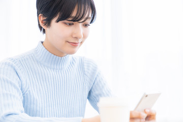 部屋でスマホを見る女性