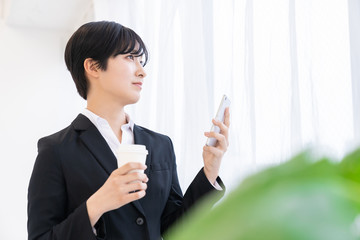 スマートフォンを見る女性　ビジネス　飲み物